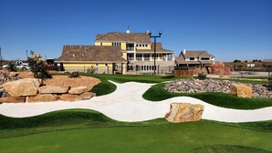 Un barrio residencial con una amplia casa de dos pisos, un césped cuidado y un campo de golf.