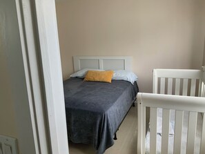 Cozy bedroom with a single bed and a crib, perfect for families.