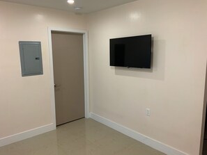 Hallway with a door leading to another room, a wall-mounted TV for entertainment, and recessed lighting.