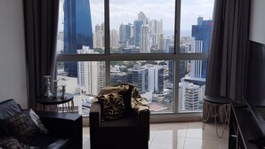 A modern living room with a large window offering a city view, a sofa, a coffee table, and a TV. - Panama from the sky in the Financial  District (Panamá)