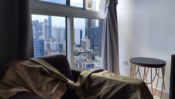 A room with a large window, a bed, a small round table, and a view of a cityscape. - Panama from the sky in the Financial  District (Panamá)