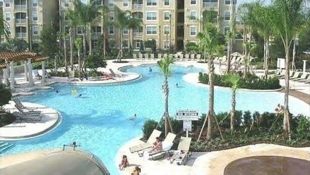 A resort with a large swimming pool, palm trees, and a multi-story building with balconies. - Windsor Wonderland!  Your Disney Getaway! Water slides, pool, arcade and more! (Kissimmee)