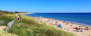 A beach with people sunbathing and swimming, a sandy shore, and a clear blue sky. - Maison Rose, La Couarde s/ mer, rénovée, en plein coeur de l île de ré ! (La Couarde-sur-Mer)