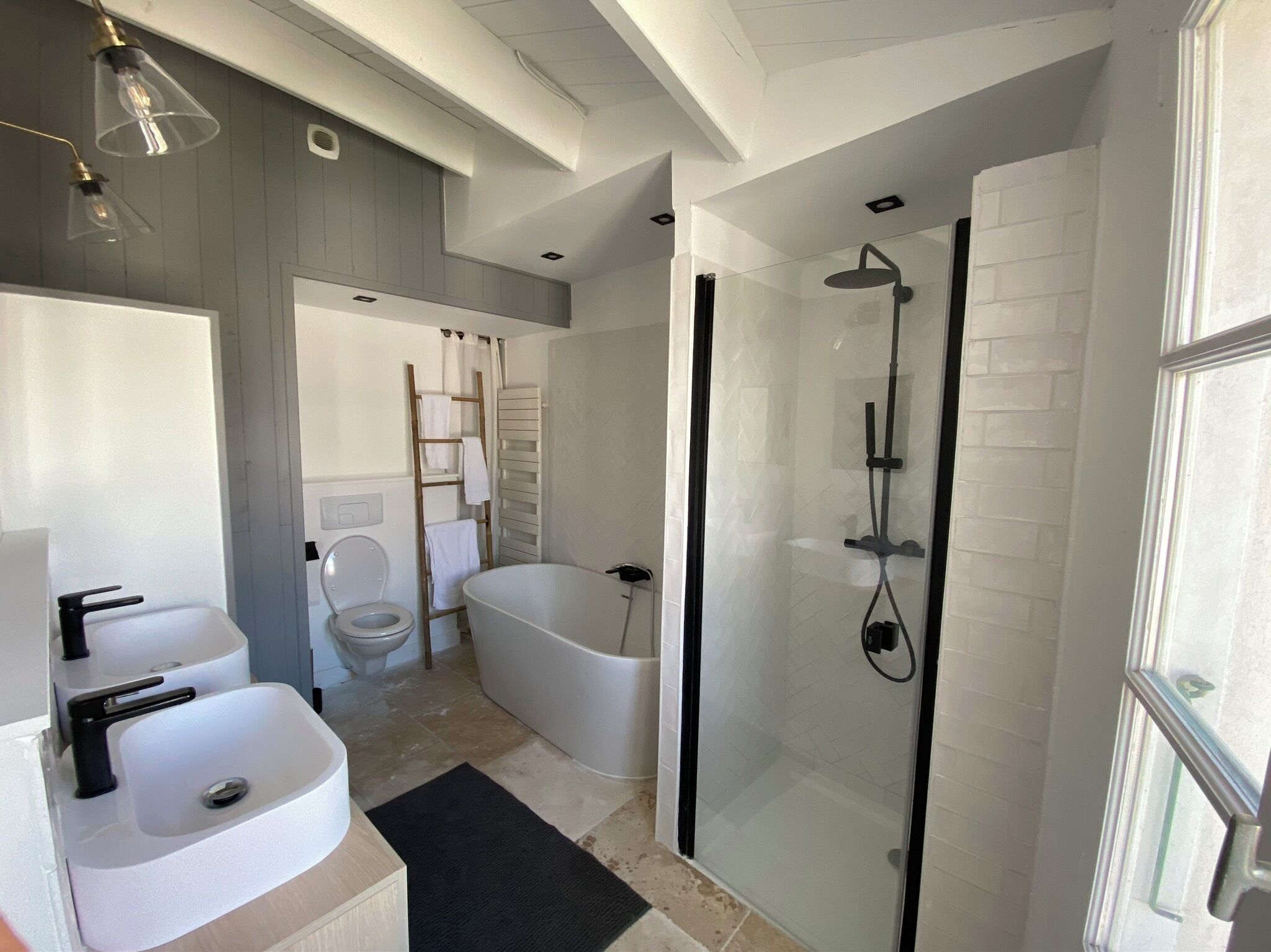 A modern bathroom with a glass-enclosed shower, a freestanding bathtub, and a toilet.