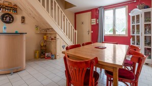 A dining area with a wooden table and red chairs, a staircase, and a cabinet with various items. - Villa Bagatelle, et son jardin - Welkeys (Montpellier)