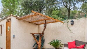 A patio with a pergola, wicker furniture, and a small table. - Villa Bagatelle, et son jardin - Welkeys (Montpellier)
