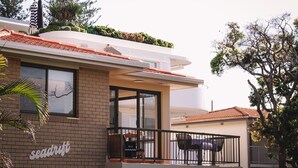Un bâtiment moderne avec une façade en briques, de grandes fenêtres et un balcon doté d’un espace salon extérieur.