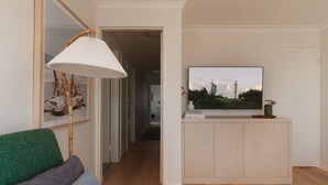 Un salon moderne avec un canapé vert, une table basse en bois et un téléviseur posé sur un meuble bas en bois clair.