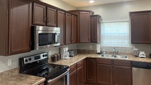 A modern kitchen with dark wooden cabinets, stainless steel appliances, granite countertops, and a window with blinds. - Newly remodeled, Hot Tub, 70n inch tv Private Entrance, Convenient location (Lebanon)