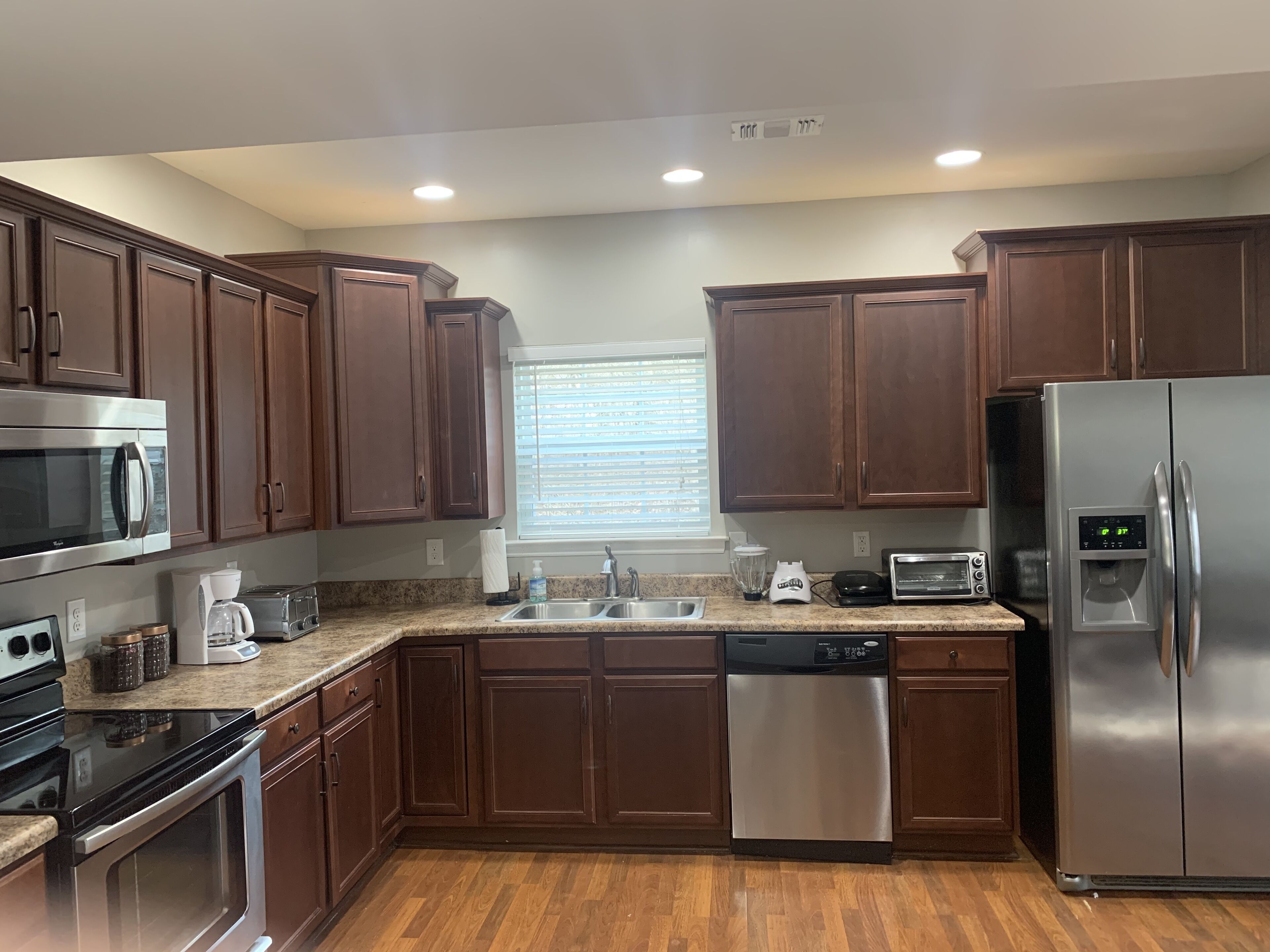 A modern kitchen with dark wooden cabinets, stainless steel appliances, and a granite countertop.
