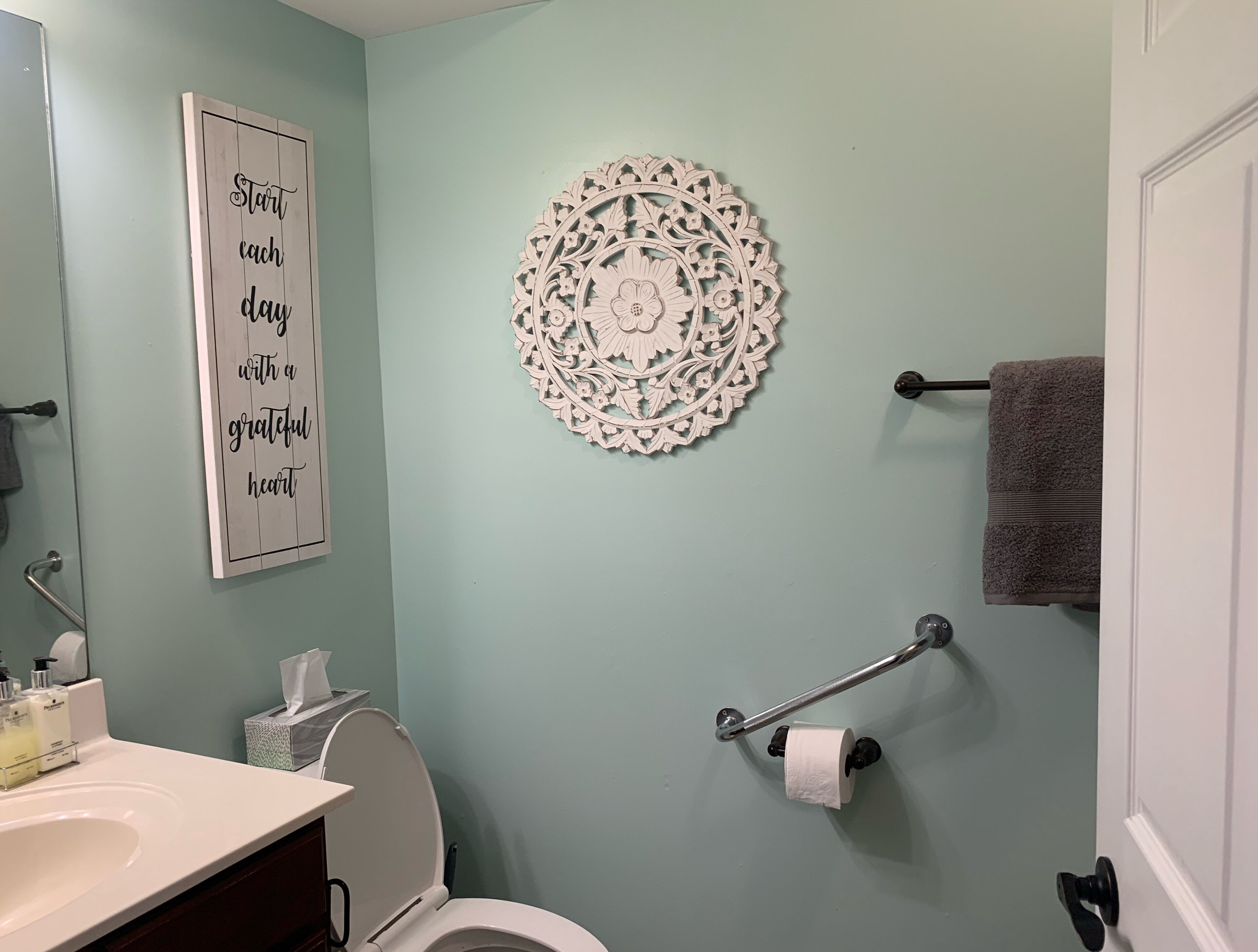Un baño con inodoro, lavamanos y un adorno de pared.