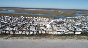 An aerial view of a residential area with houses arranged in a grid pattern, a main road, and a river in the background.
