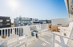A deck with white railings, wicker chairs, and a table. - SIC Home- Prime Location! (Sea Isle City)