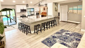 A modern kitchen with a central island, bar stools, and a ceiling fan. - SPACIOUS home, private POOL,5 mins to beach! Walk to Publix. Great for families! (Seminole)