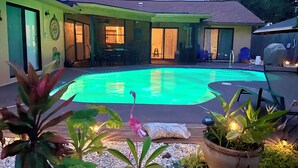 A backyard with a swimming pool, a covered patio area, and potted plants. - SPACIOUS home, private POOL,5 mins to beach! Walk to Publix. Great for families! (Seminole)