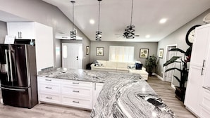 A modern kitchen with a marble countertop, white cabinetry, and a built-in refrigerator. There is a ceiling fan and pendant lighting. - SPACIOUS home, private POOL,5 mins to beach! Walk to Publix. Great for families! (Seminole)