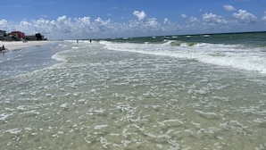 A beach with clear water, a pier, and buildings in the background. - SPACIOUS home, private POOL,5 mins to beach! Walk to Publix. Great for families! (Seminole)