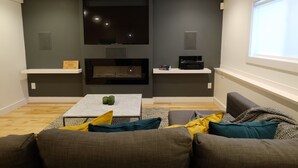A modern living room with a flat-screen TV, fireplace, and built-in shelves.