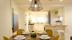 A dining area with a round table set for four, yellow chairs, and a modern pendant light.