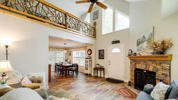 A spacious living area with a fireplace, a dining area, and a staircase leading to an upper level. - 'Greystone' Creekside Cabin: Hike, Fish & Explore! (Elk Park)