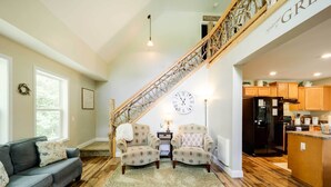 A spacious living room with a staircase, a dining area, and a kitchen. - 'Greystone' Creekside Cabin: Hike, Fish & Explore! (Elk Park)