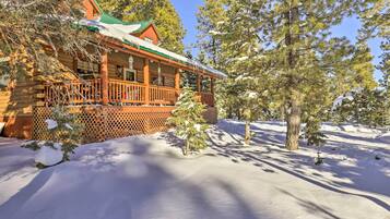 A log cabin with a porch and snow-covered ground.