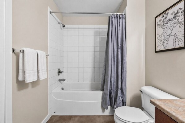 A bathroom with a bathtub, toilet, and a shower curtain.