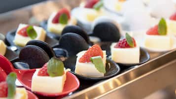 Una bandeja de postres con diversas opciones pequeñas, incluyendo uno con fresa y una hoja de menta como adorno.