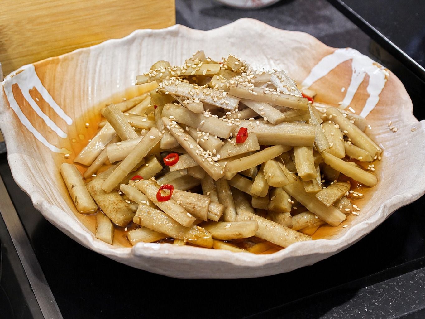 A bowl of food with sesame seeds and red chili slices.