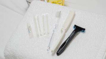 A white towel with a razor, toothbrush, and several clear tubes on it.