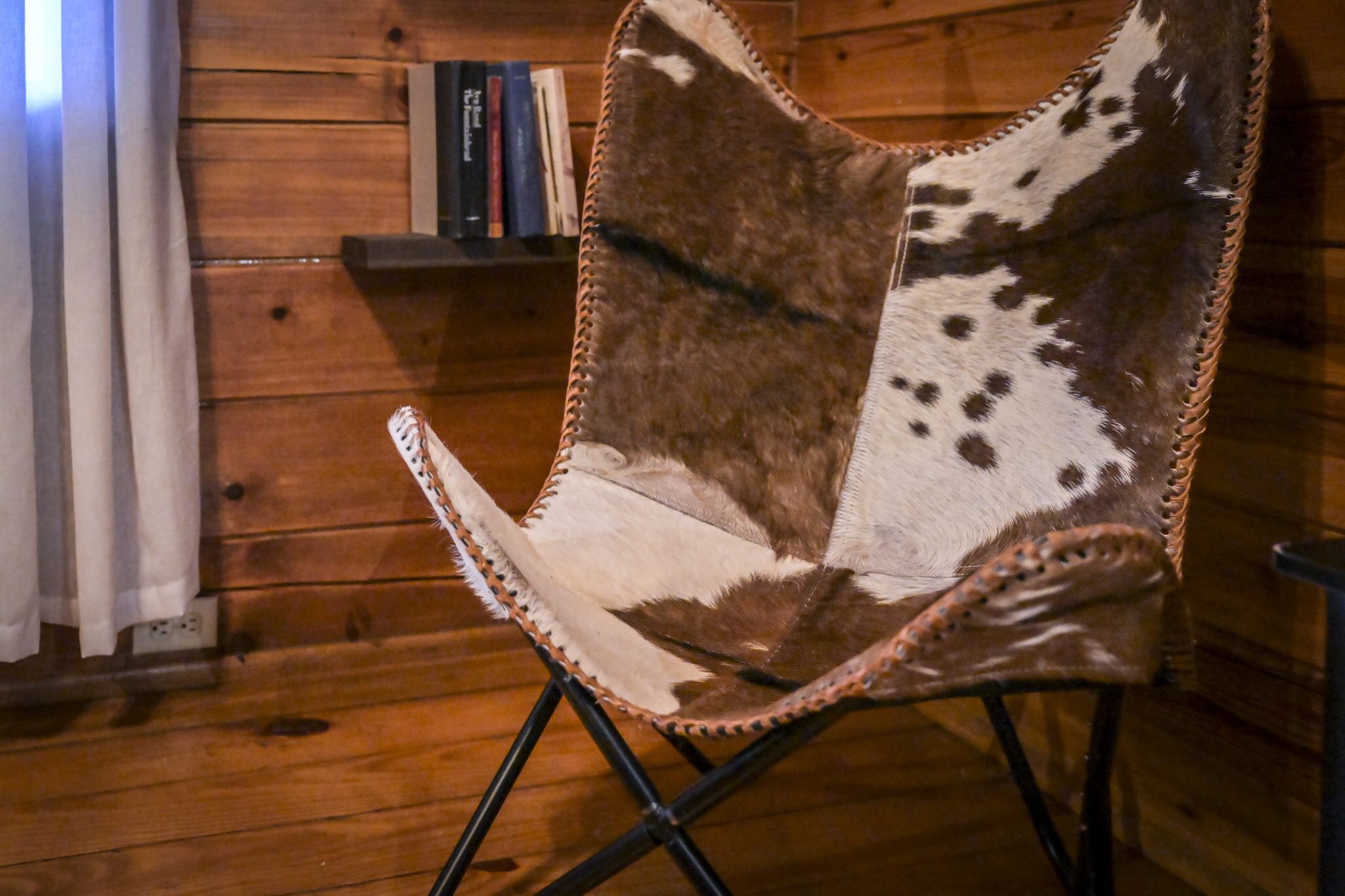 A rustic wooden interior with a leather chair and a bookshelf.
