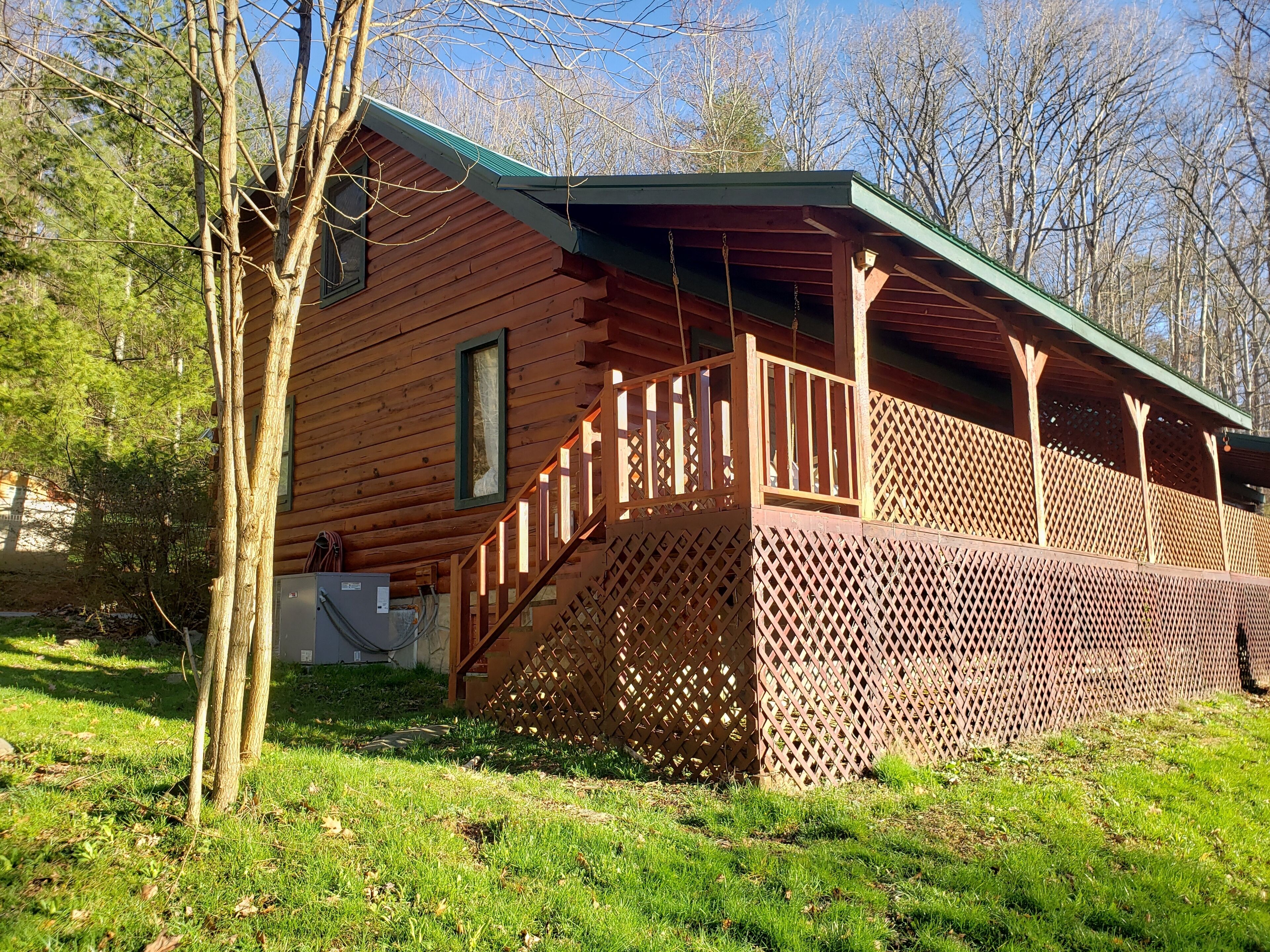 A wooden cabin with a covered porch and a staircase leading to a deck.