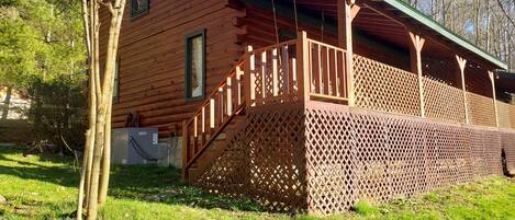 A wooden cabin with a covered porch and a staircase leading to a deck.