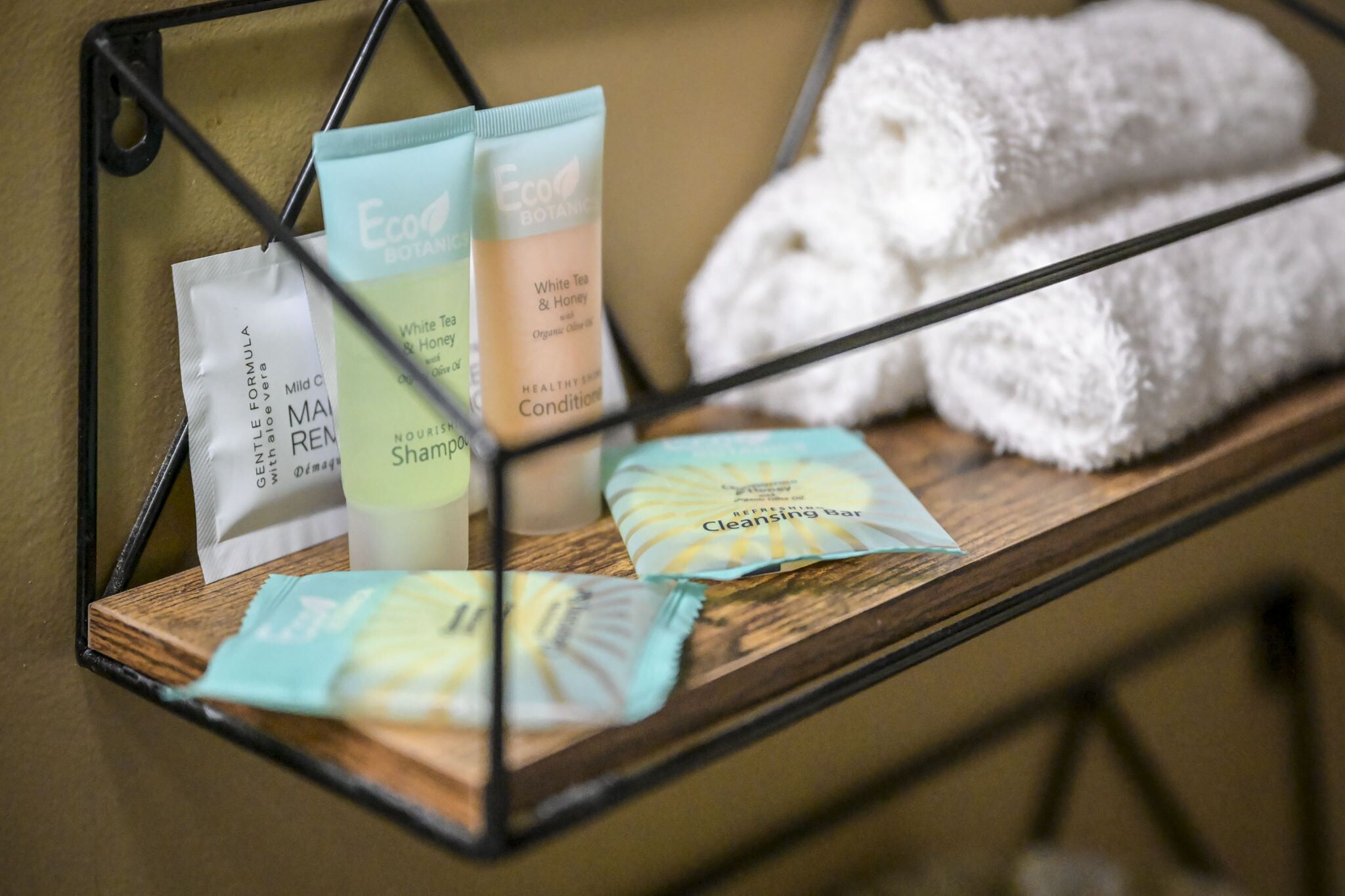 A shelf with various skincare products, including a cleansing bar and a white tea and honey conditioner.