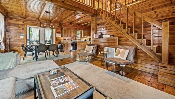 A spacious log cabin interior with a central living area, a kitchen, and a staircase. - Log Cabin w/Hot Tub & All the Amenities. Close to the Park & Pigeon Forge (sevierville)