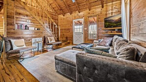 A wooden interior with a sofa, ottoman, and a television on a wall. - Log Cabin w/Hot Tub & All the Amenities. Close to the Park & Pigeon Forge (sevierville)