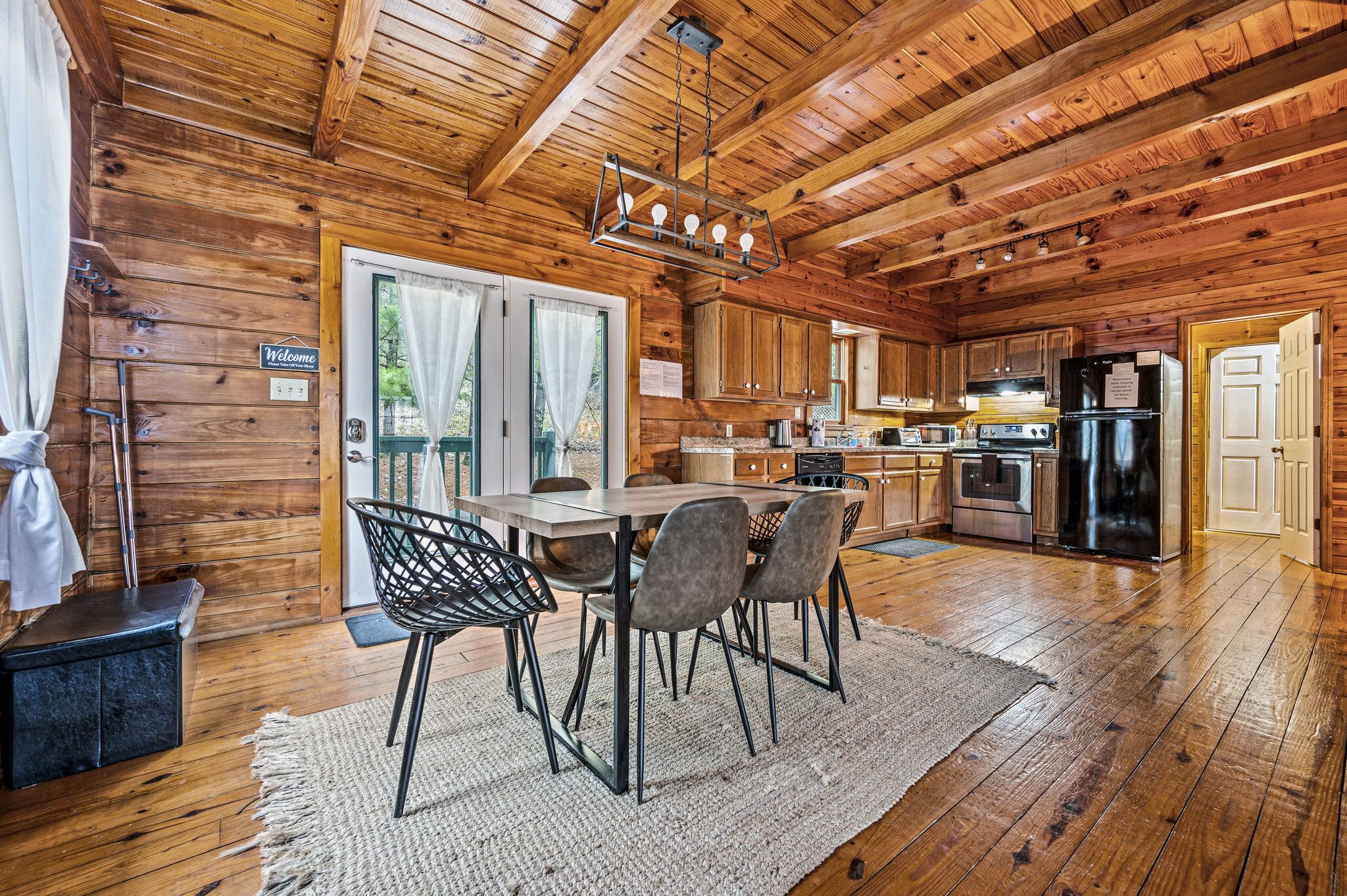 Interno di una baita in legno con angolo ristoro, cucina e una grande finestra.
