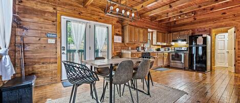 Interno di una baita in legno con angolo ristoro, cucina e una grande finestra.