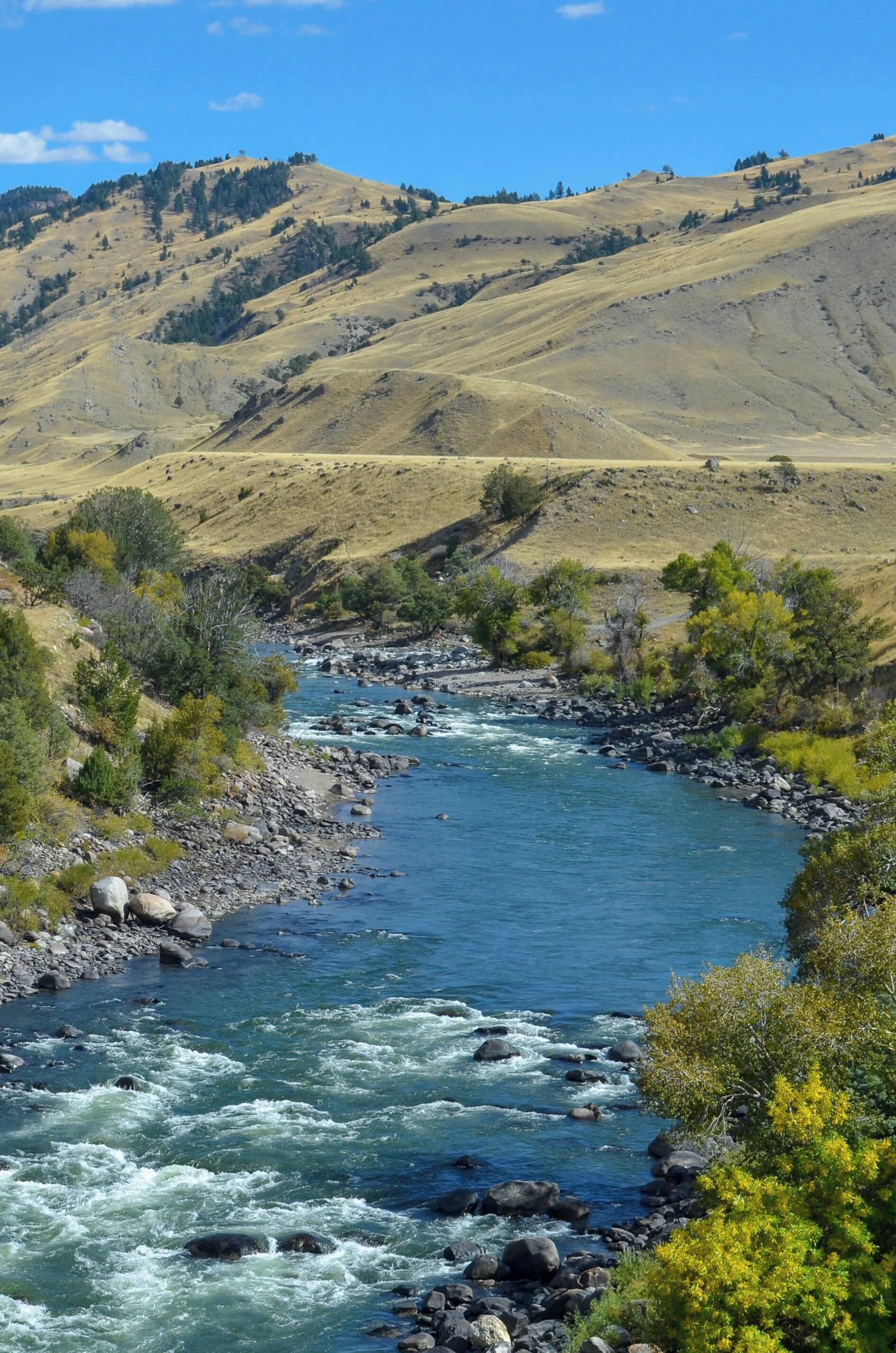Une rivière qui traverse une vallée, avec des collines en arrière-plan.