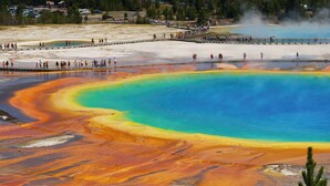 Une grande piscine géothermique aux couleurs vives, dotée d’une plateforme d’observation et bordée de personnes.