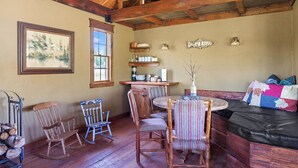 L’intérieur d’un chalet rustique, avec des meubles en bois, une table à manger et un coin salon confortable.