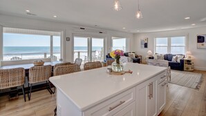 A spacious living area with a large island, wicker furniture, and a view of the ocean.
