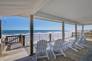 A wooden deck with white Adirondack chairs overlooking a beach. - Modern Oceanfront Luxury Topsail Island Beach House Walkable to Surf City Pier  (Surf City)