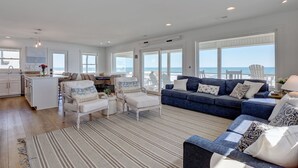 A spacious living area with a large sofa, a dining table, and a kitchen area.