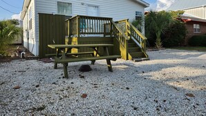 Une maison de plain-pied dotée d’un patio couvert, d’un escalier en bois et d’une table de pique-nique.