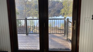 A wooden deck with a metal railing overlooking a lake, surrounded by trees. - Family Adventure at Lake Wissota Lodge + Studio (Jim Falls)