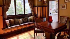A room with a wooden bench, a dining table, chairs, and a window with curtains.