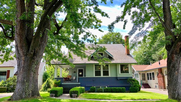 A two-story house with a front porch, a chimney, and a well-maintained lawn.
