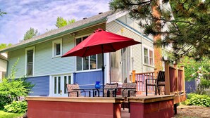A covered porch with outdoor furniture and a red umbrella.