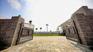 A paved entrance with stone walls and decorative metal gates. - Neo Farm House with Pool, Beach Volley Ball & 5Beds(A/C) (Batasingaram)
